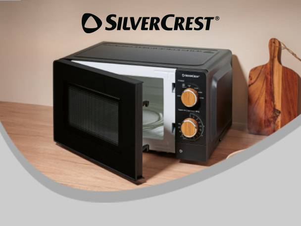 Black microwave oven with wooden knobs, door open, on a wooden counter.