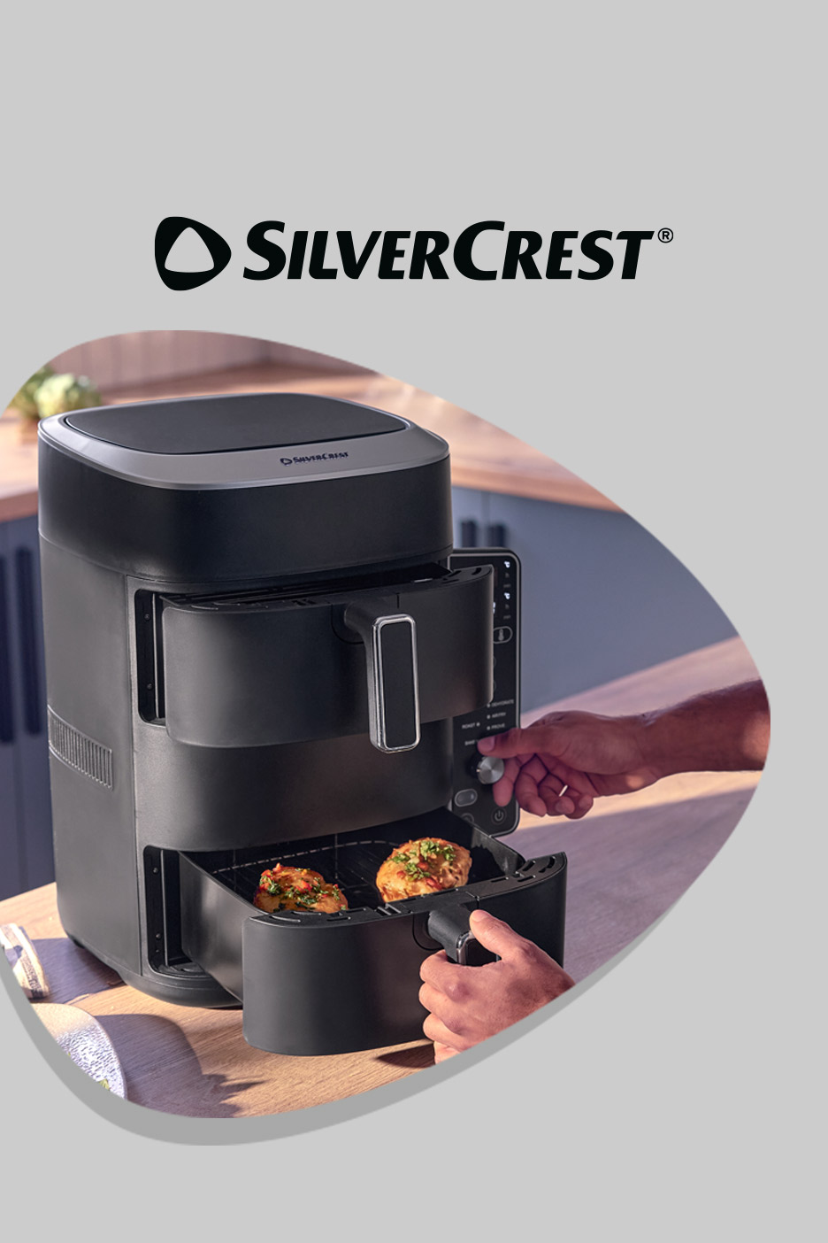 Black dual-basket air fryer on a wooden counter with food inside, a hand adjusting settings.