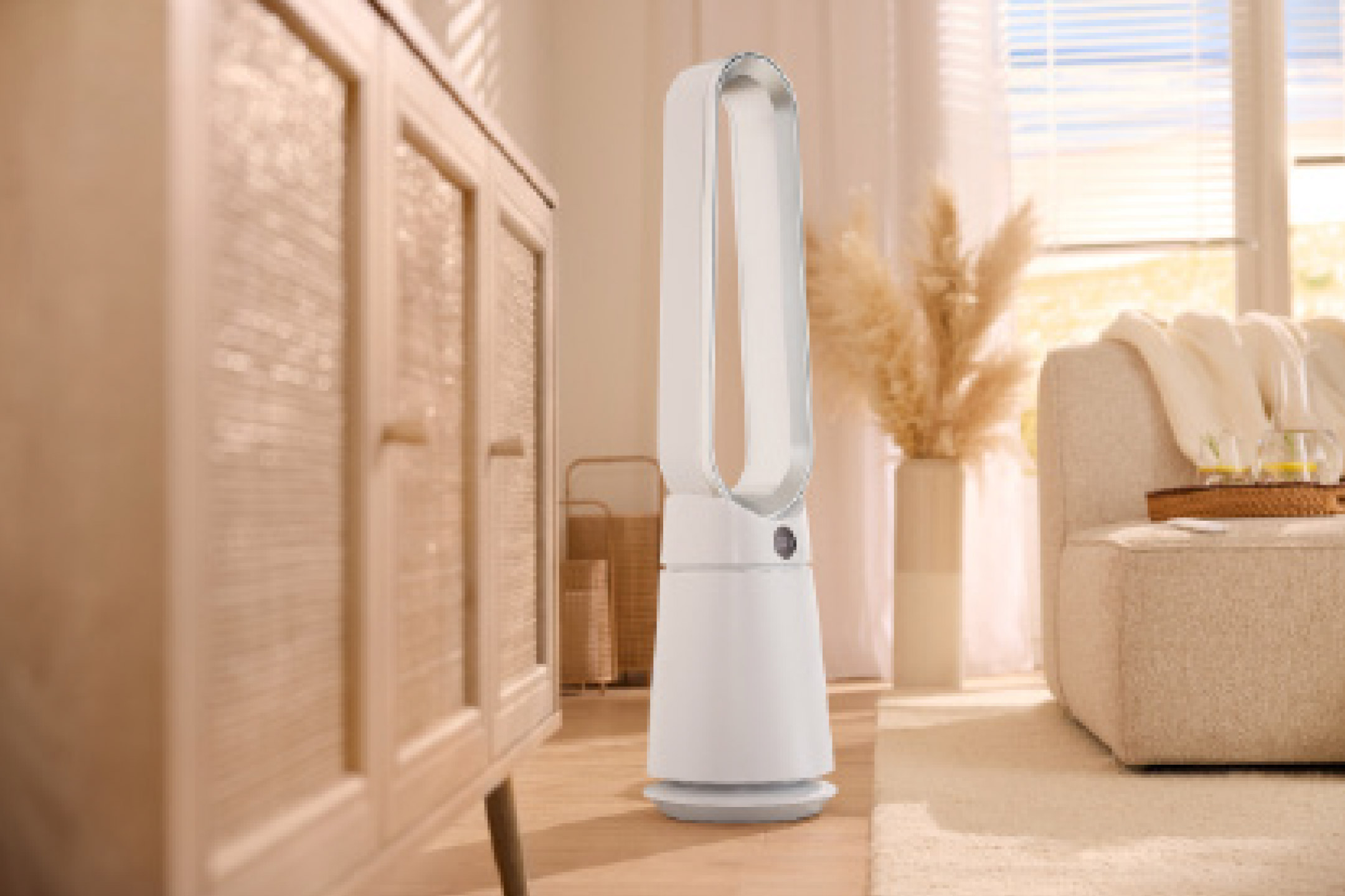 A white bladeless fan in a bright, modern living room with a wooden cabinet and sofa.