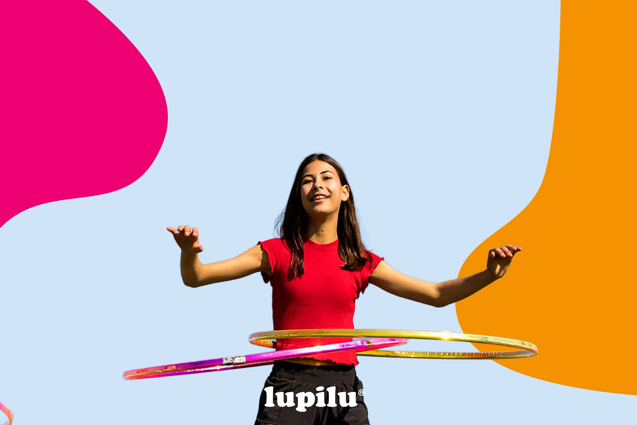 A young girl in a red top and black shorts hula hooping with two colorful hoops.