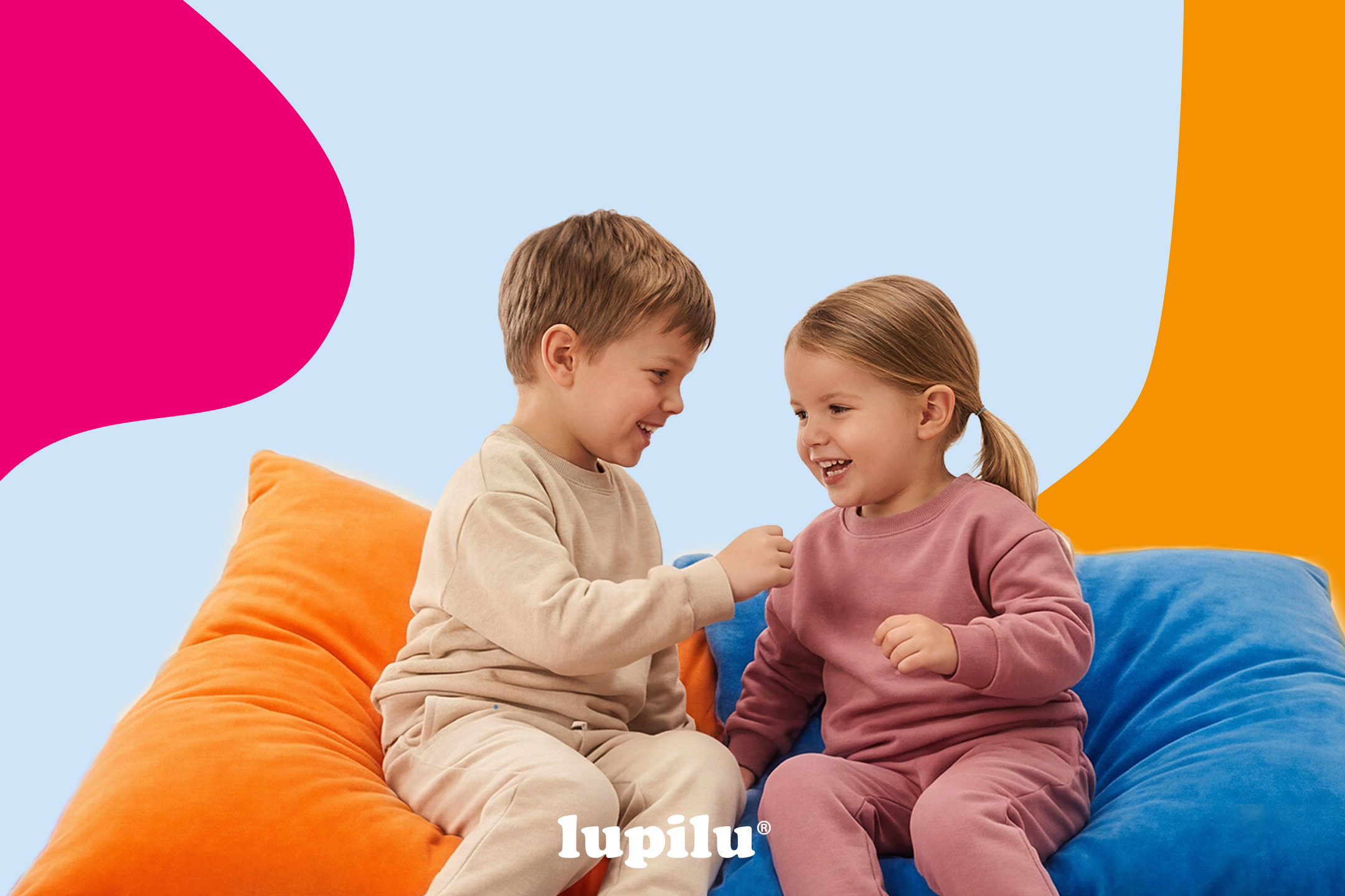 Two children in matching loungewear sets, sitting on colorful beanbags and smiling.