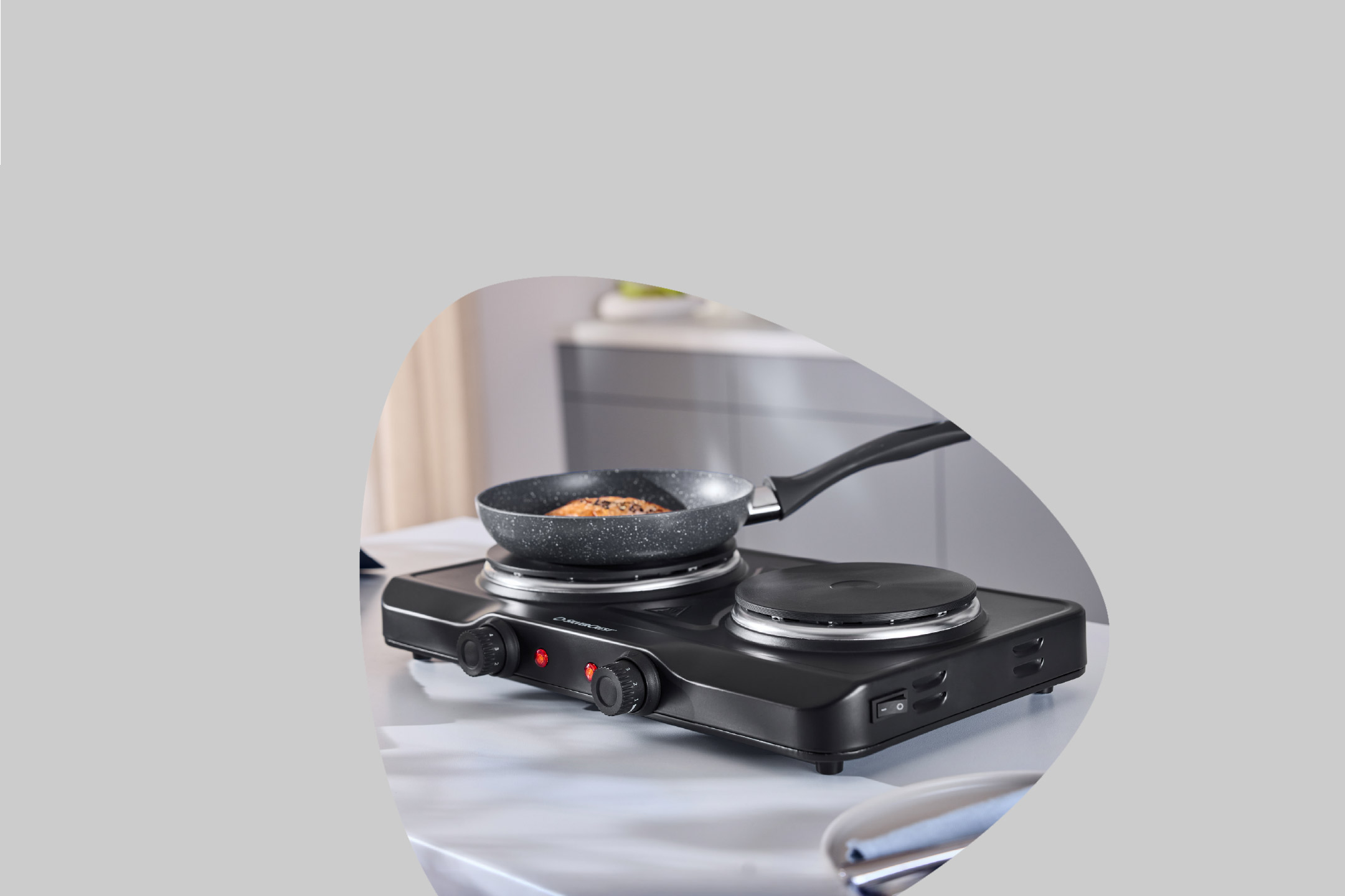 Portable double hot plate with a frying pan cooking food on one burner