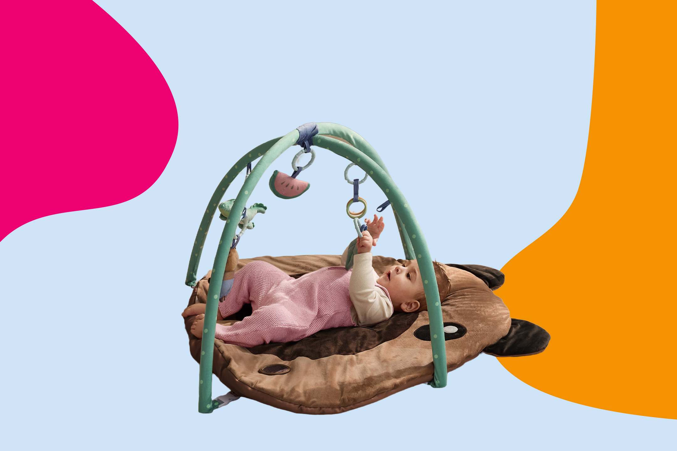 Baby lying on a playmat with an activity arch, reaching for hanging toys.
