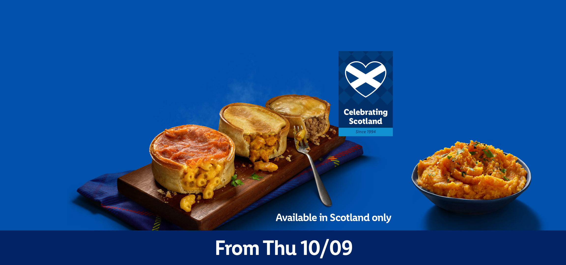 Three Scottish pies (mac and cheese, haggis, steak) and a bowl of neeps, on a blue background. Text: From Thu 10/09. Available in Scotland only. Celebrating Scotland since 1994.