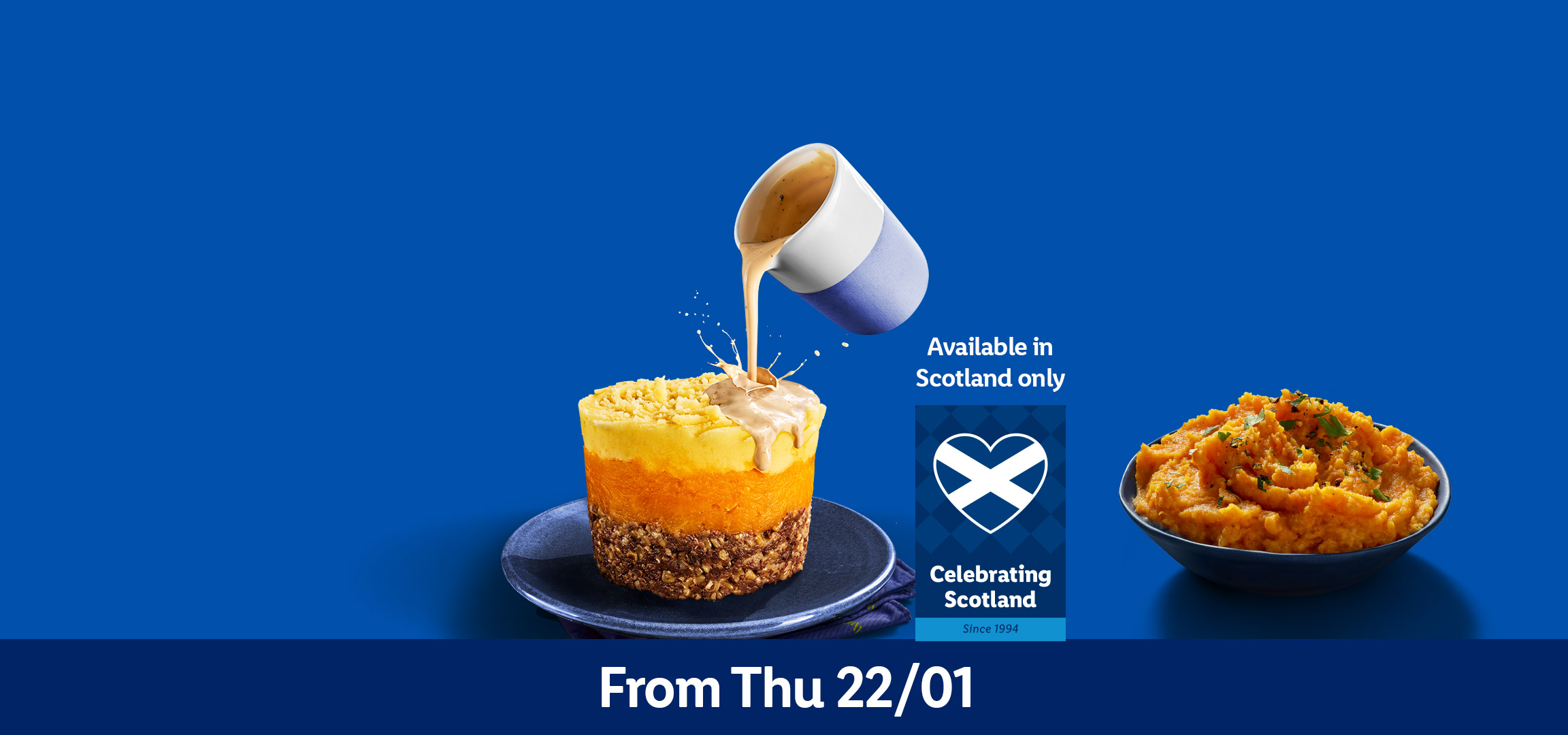 Whisky glass and a layered dish with haggis, neeps, and tatties, with sauce being poured.