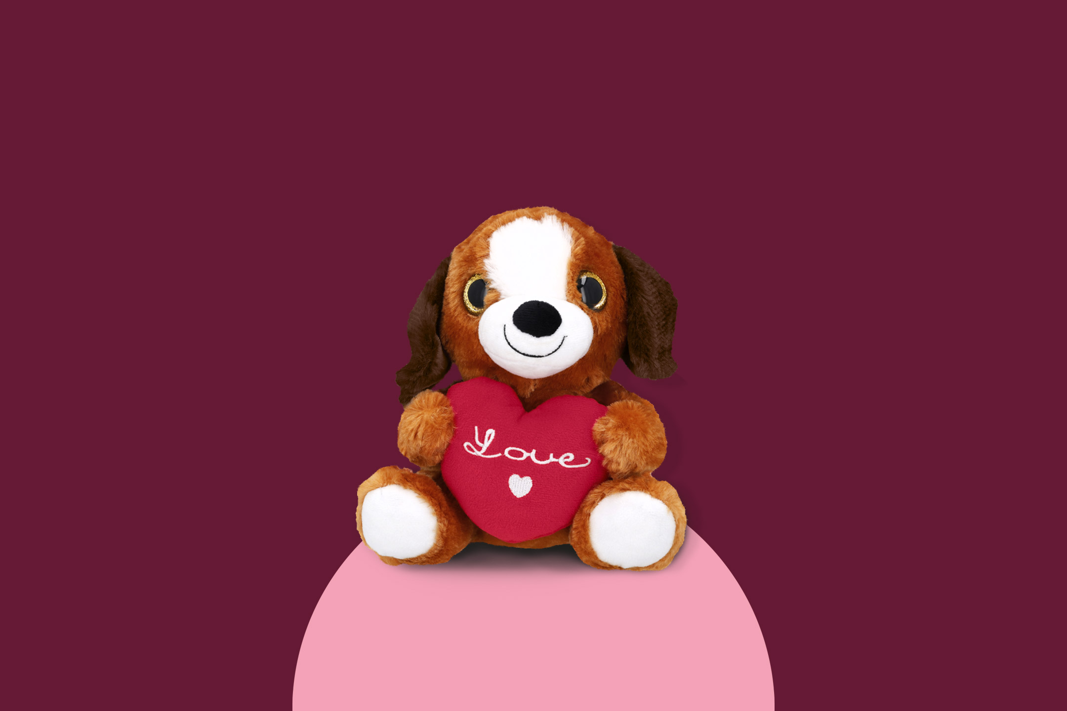 A brown and white plush dog holding a red heart pillow with 'Love' written on it.