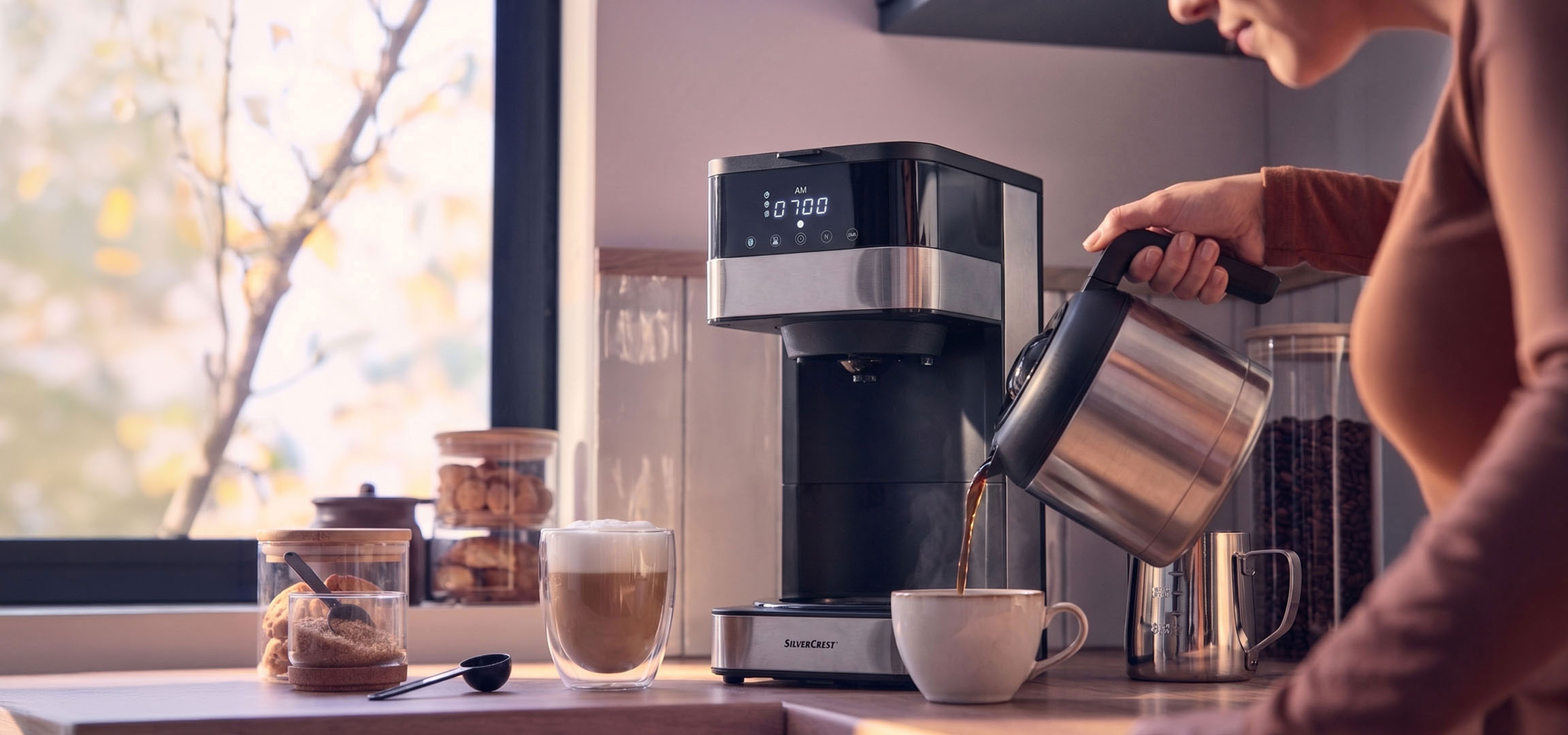 aiLabeling.aiLabelForImageAltText: Coffee machine pouring coffee into a cup, with a bright window in the background.