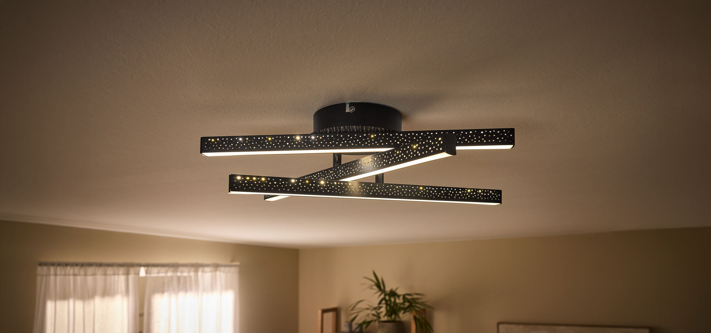 Modern LED ceiling light with black, perforated bars and warm light.