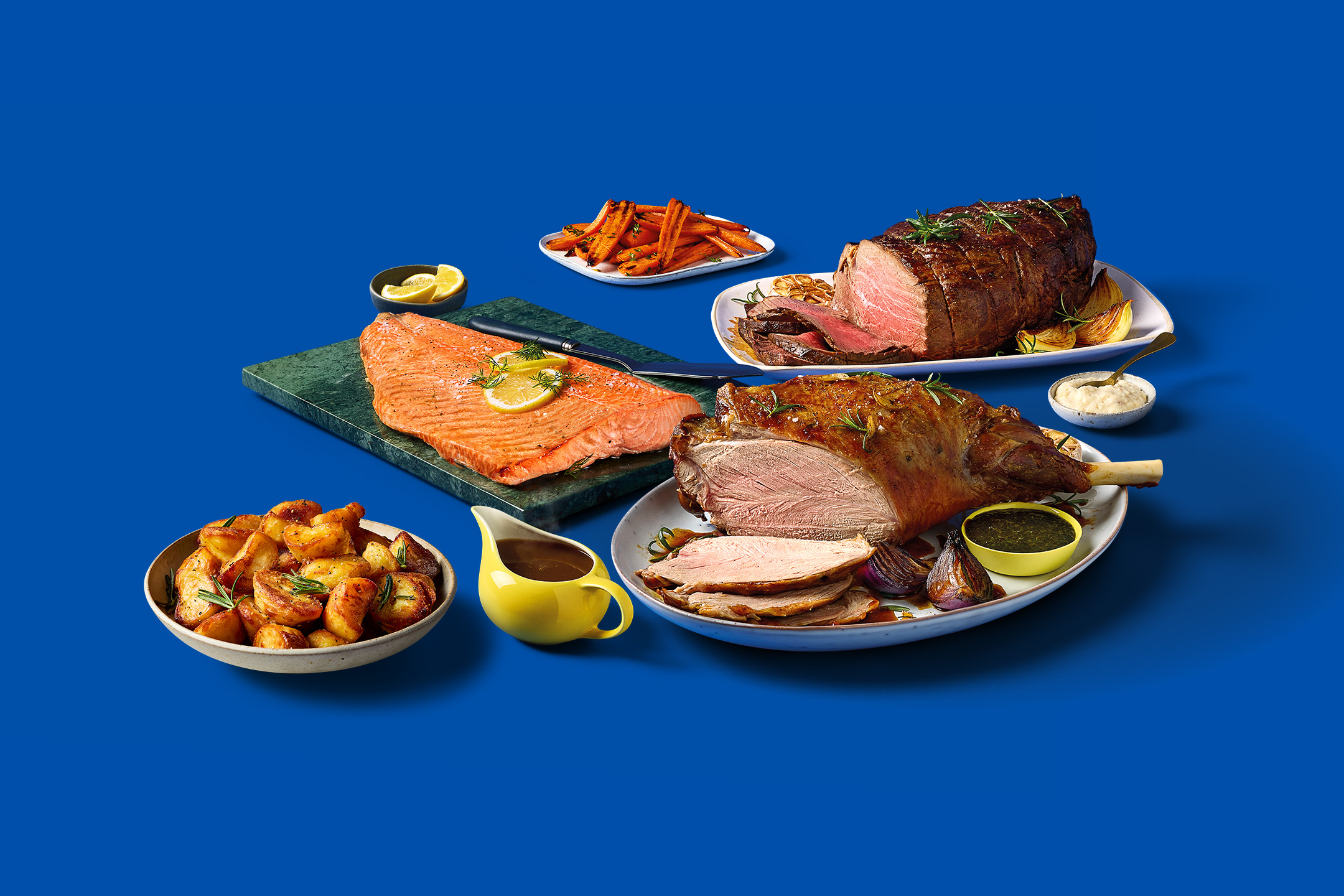 A feast of roasted meats including beef, lamb, and salmon, with roasted potatoes and carrots.