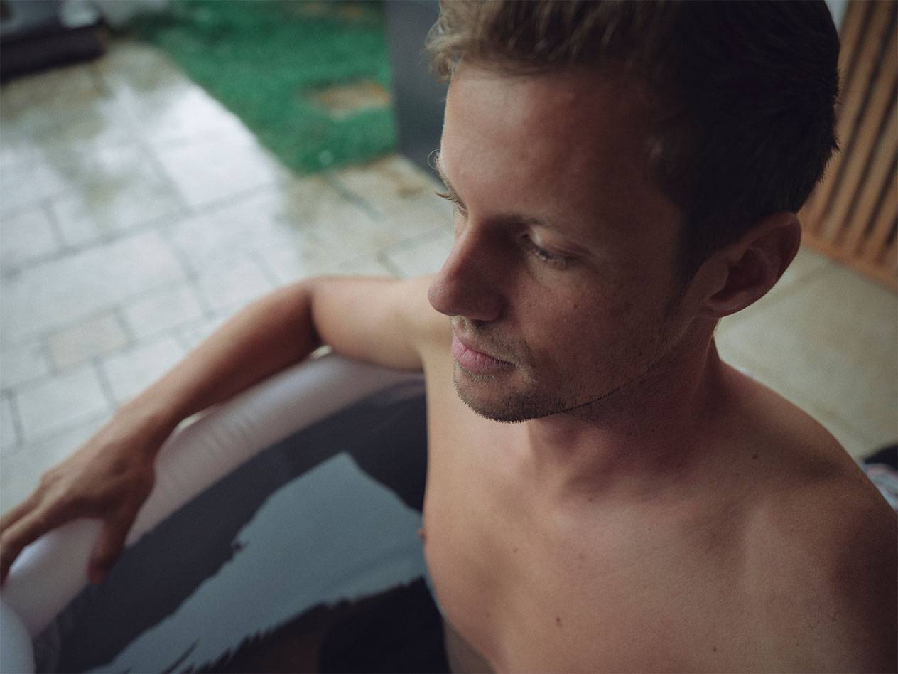 Man relaxing in an inflatable hot tub outdoors.