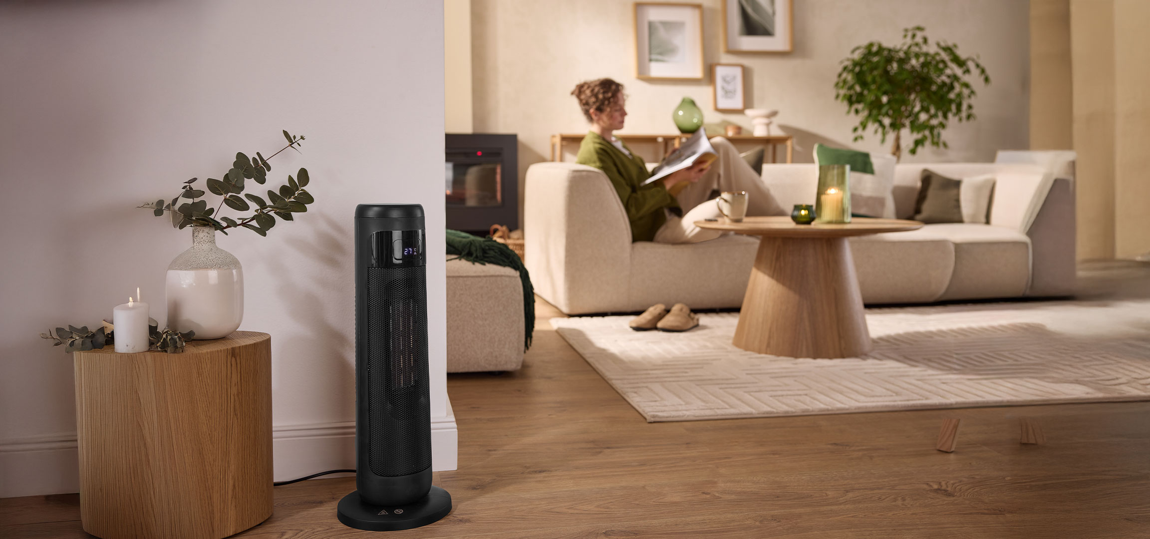 aiLabeling.aiLabelForImageAltText: A modern black tower heater in a cozy, warm living room with a person relaxing on the sofa.