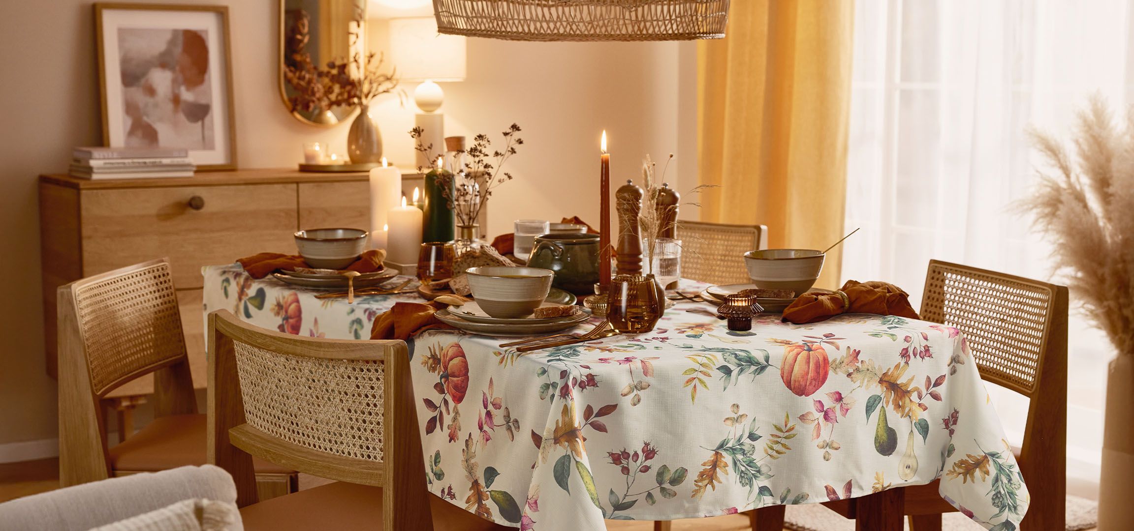 Dining room with a table set for a meal, featuring a floral tablecloth and warm lighting.