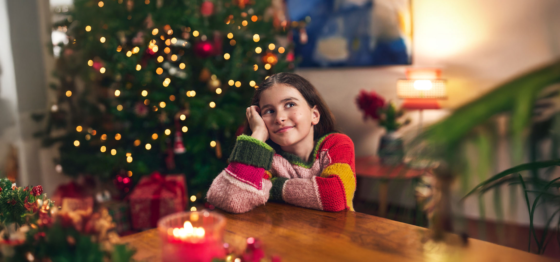 Girl dreaming during Christmas, with a Christmas tree and presents in the background.