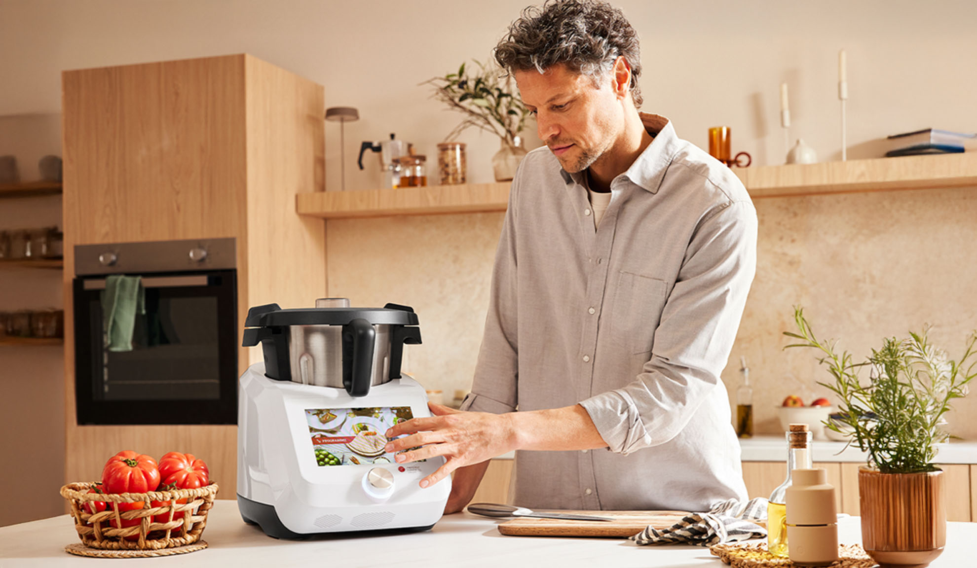 A man using a Monsieur Cuisine food processor in a modern kitchen.