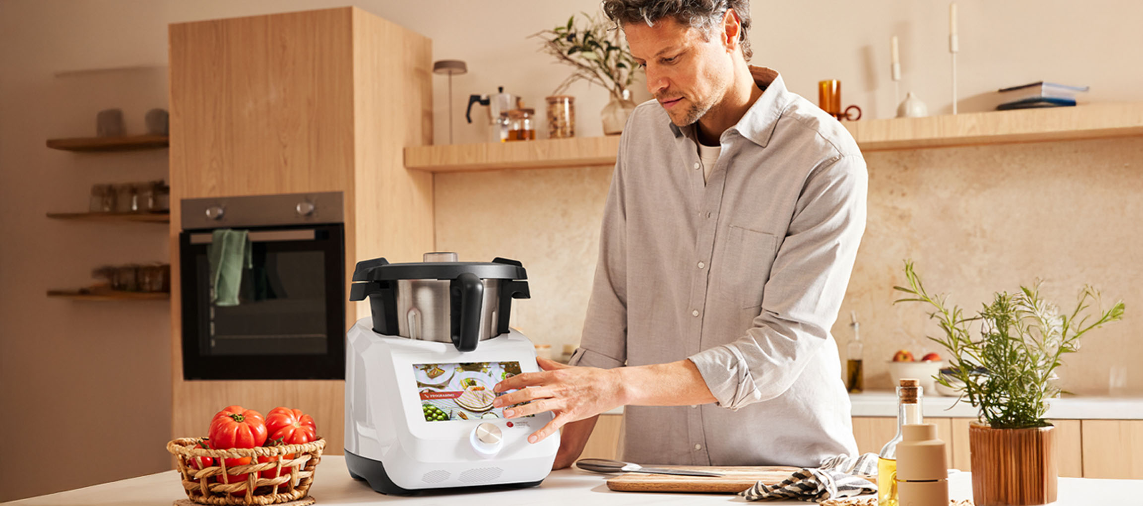 Man using a white Silvercrest Monsieur Cuisine smart food processor in a modern kitchen.