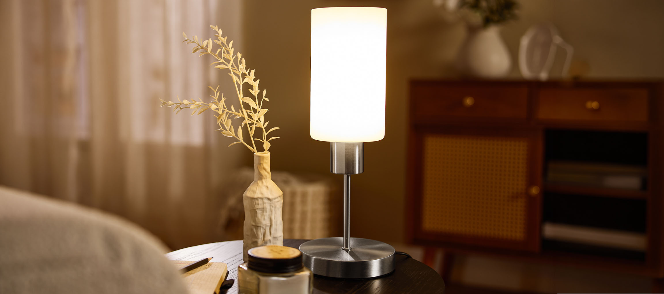 Table lamp with a vase and dried plants on a bedside table.