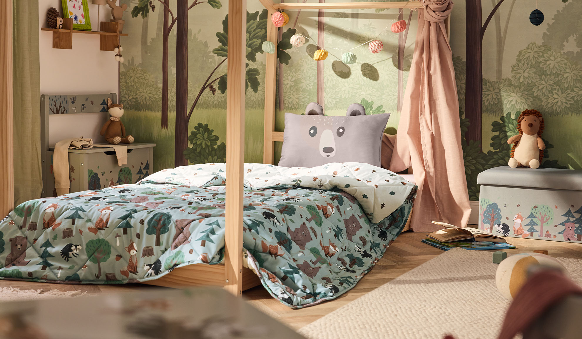 Children's bedroom with a wooden bed, bear pillow, and forest-themed duvet.