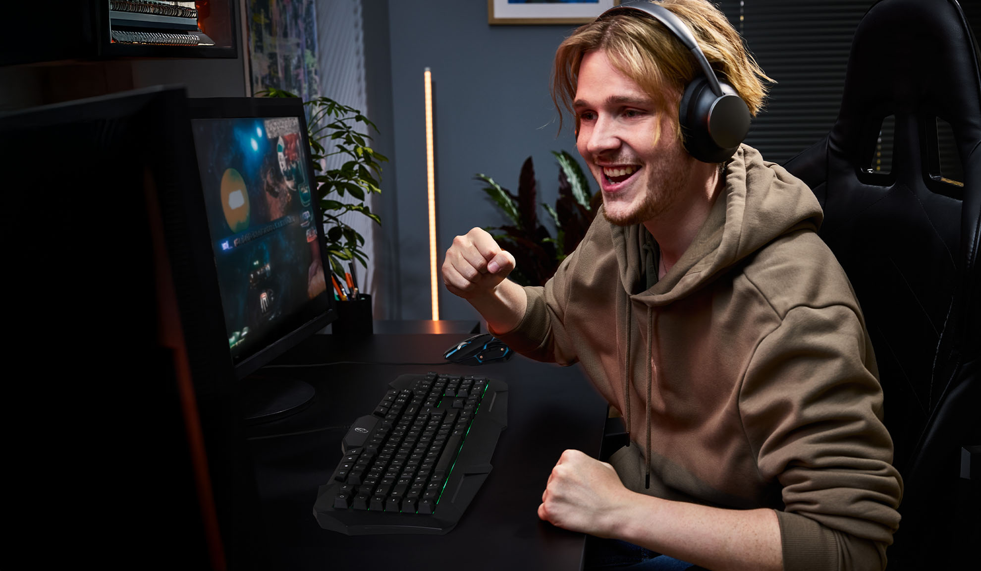Young man with headphones playing video games with a gaming keyboard and mouse.
