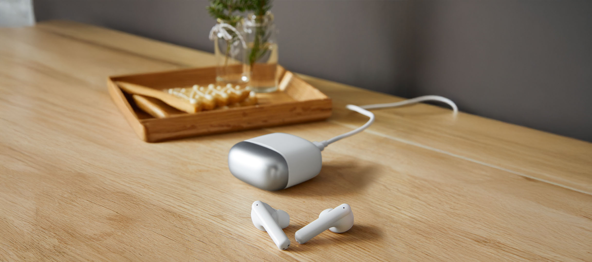 White earbuds and a portable charger on a wooden table.