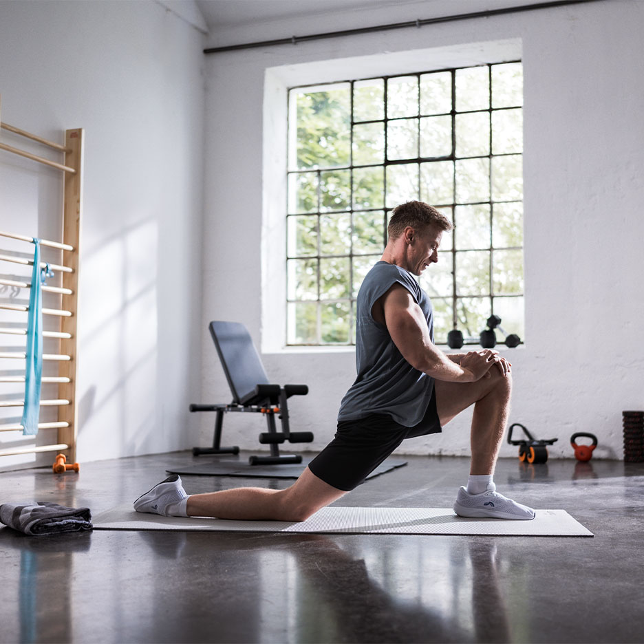Man stretching on a yoga mat in a gym.
