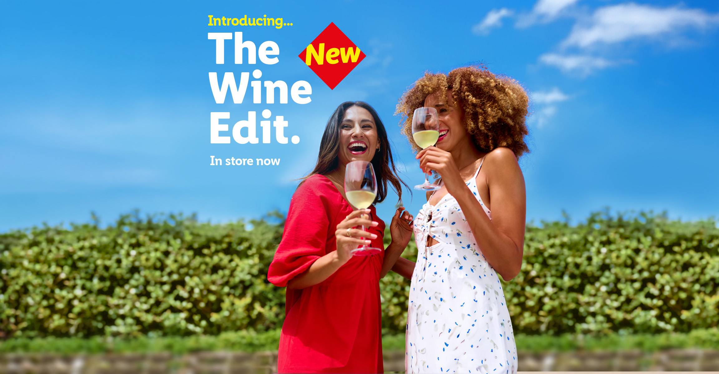 Two women enjoying wine outdoors, promoting 'The New Wine Edit' available in store now.