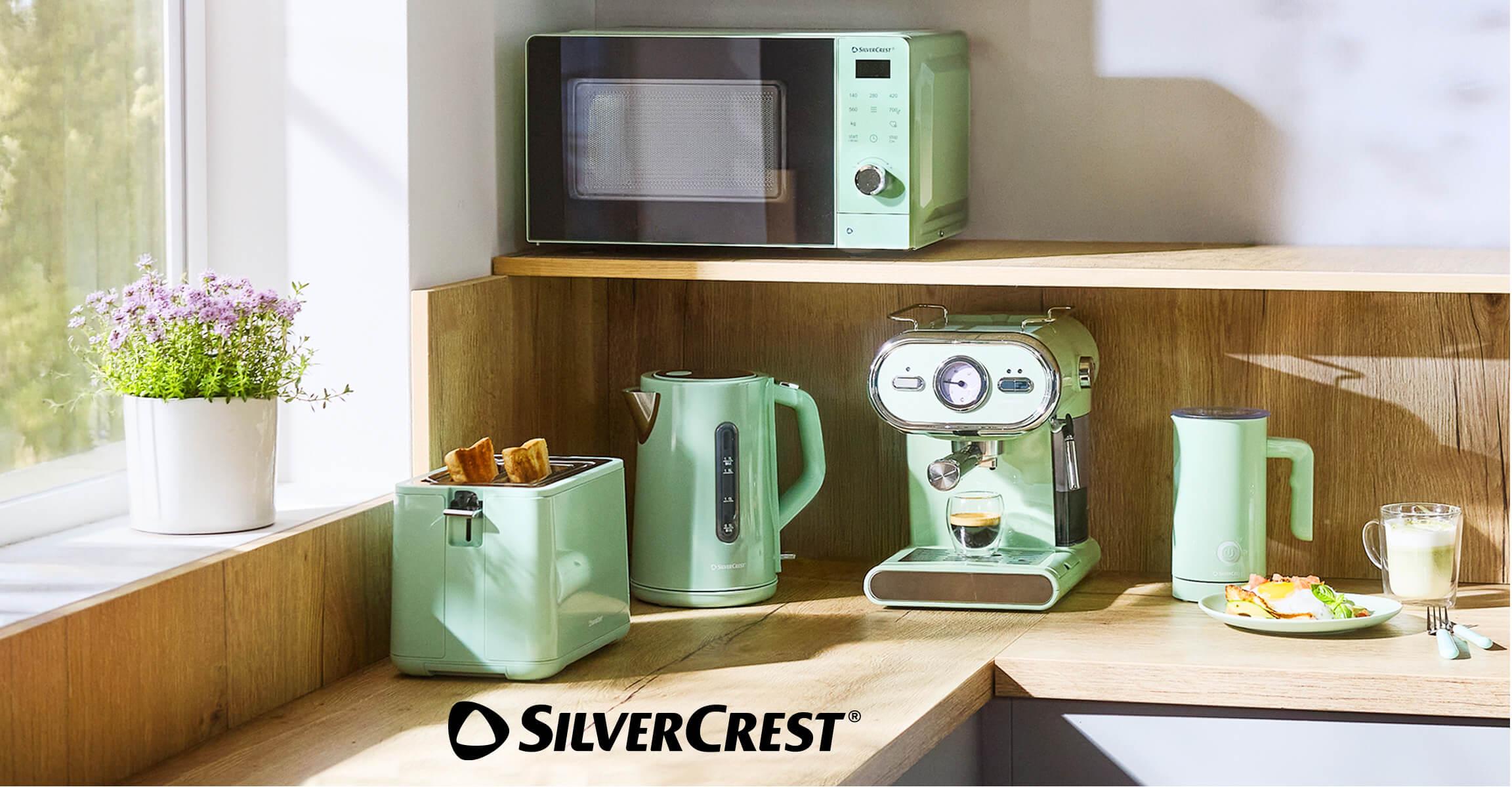 Mint green kitchen appliances: microwave, toaster, kettle, and espresso machine on a wooden counter.