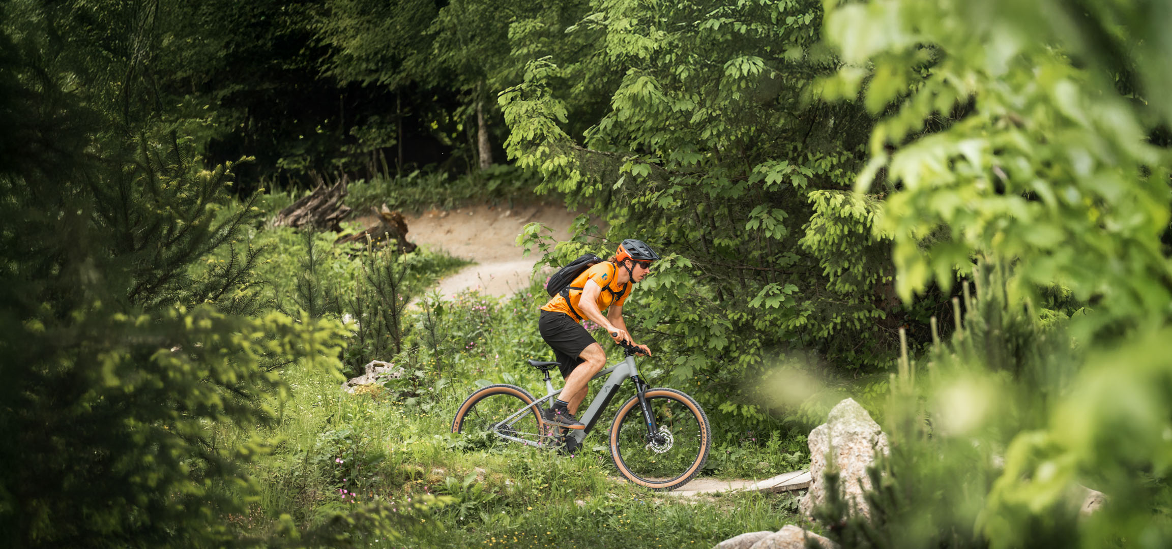 A cyclist enjoys an e-bike ride on a forest trail.