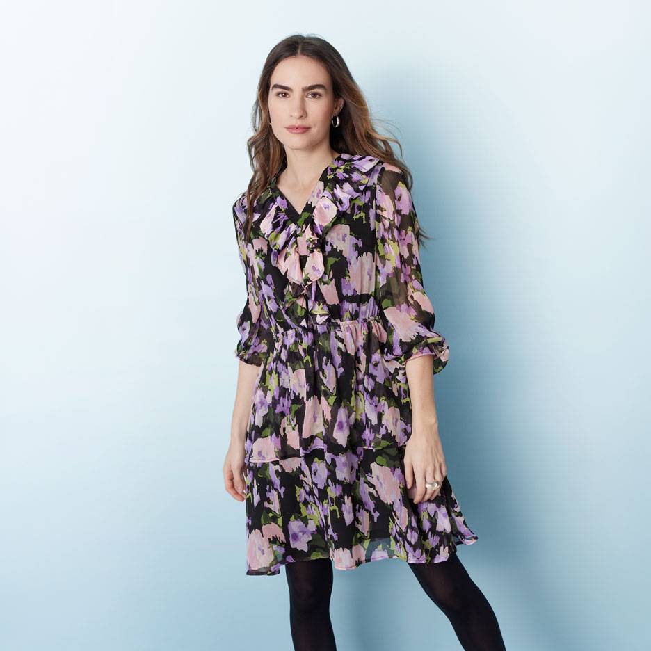 Woman in black, purple, and pink floral ruffled dress and black tights.