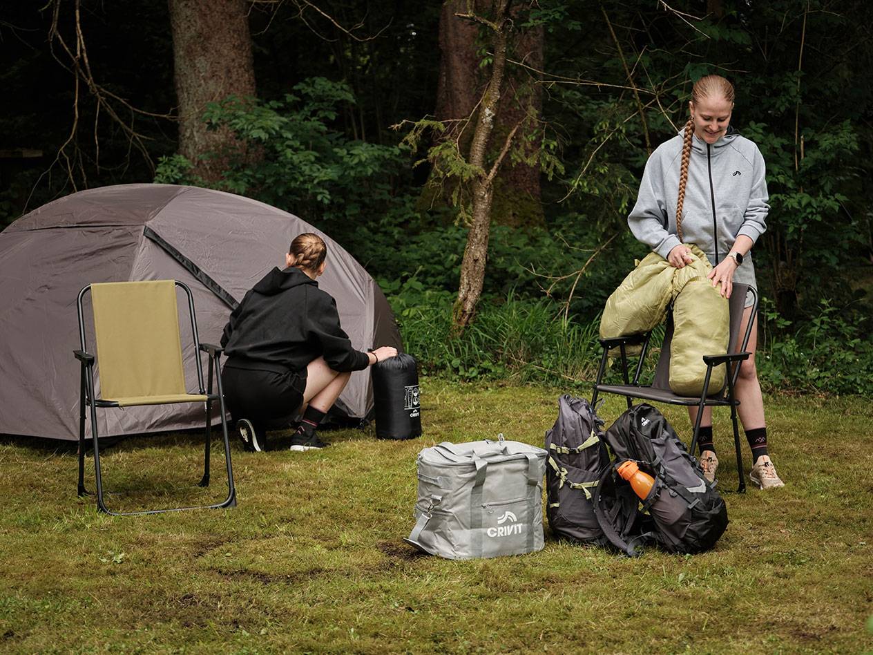 Two people unpack camping gear, including a Crivit cooler bag and tent.