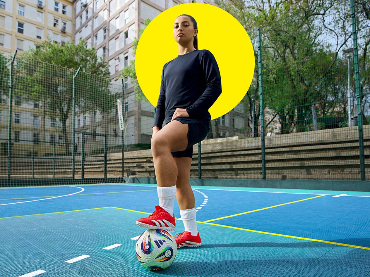 Soccer player in Adidas shoes on a blue court.