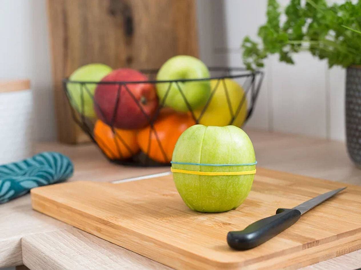 Apple secured with rubber bands on a wooden board.