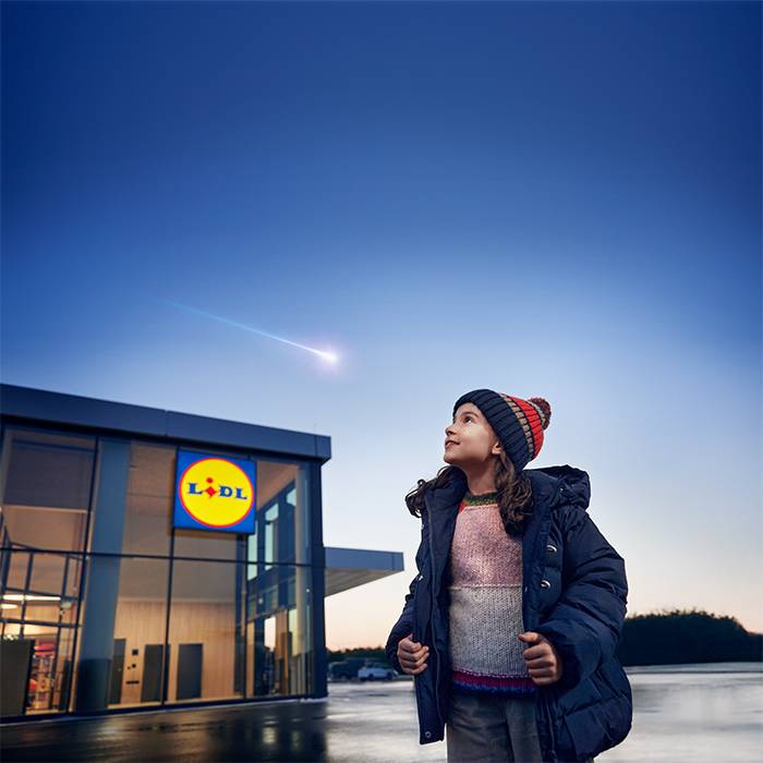 A girl looks at a shooting star above a Lidl store.
